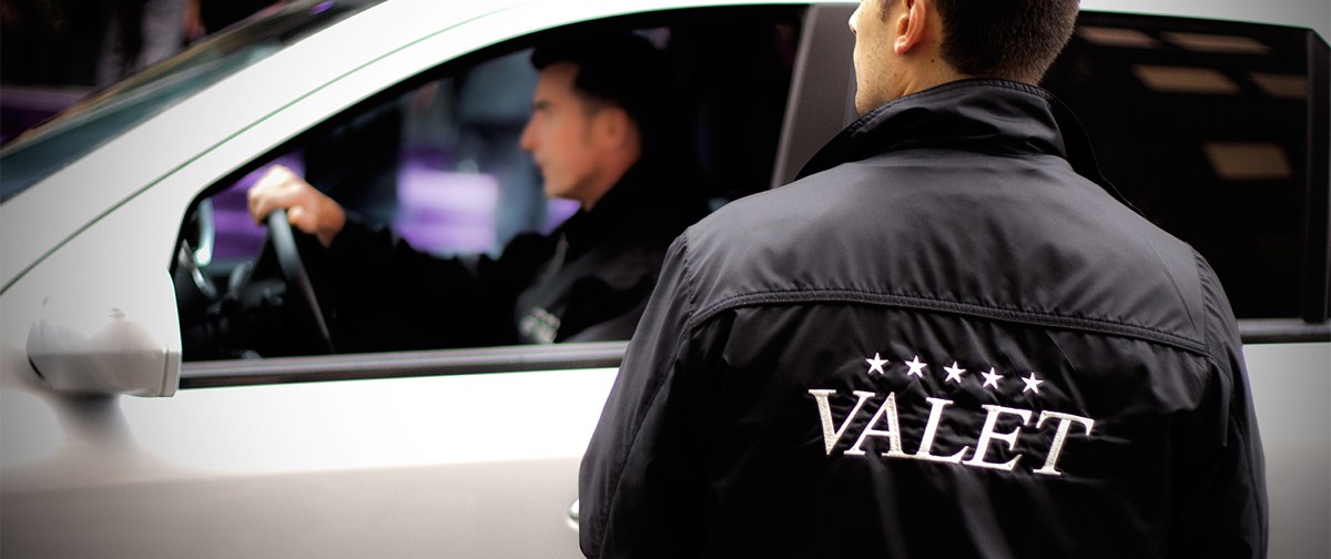 A valet attendant taking a customer’s car at the lot
